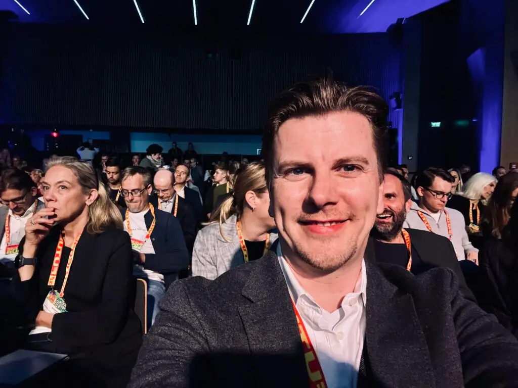Hendrik Luehrsen macht ein Selfie im Publikum des DLD Future Hub 2025. Im Vordergrund er mit Konferenz-Badge, im Hintergrund weitere Teilnehmerinnen und Teilnehmer im Saal.