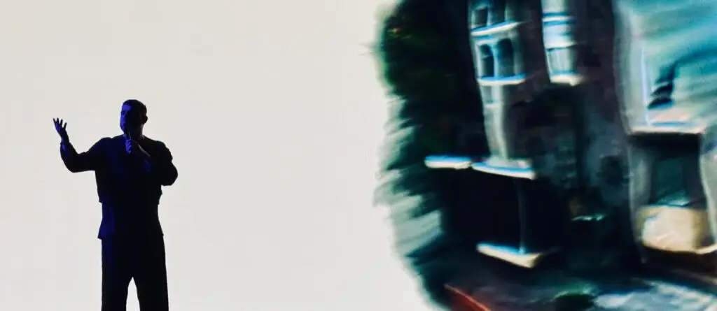 Opening Performance von Harry Yeff beim DLD Future Hub 2025: Silhouette des Künstlers vor hellem Hintergrund, daneben eine digital verfremdete Projektion eines Gebäudes.