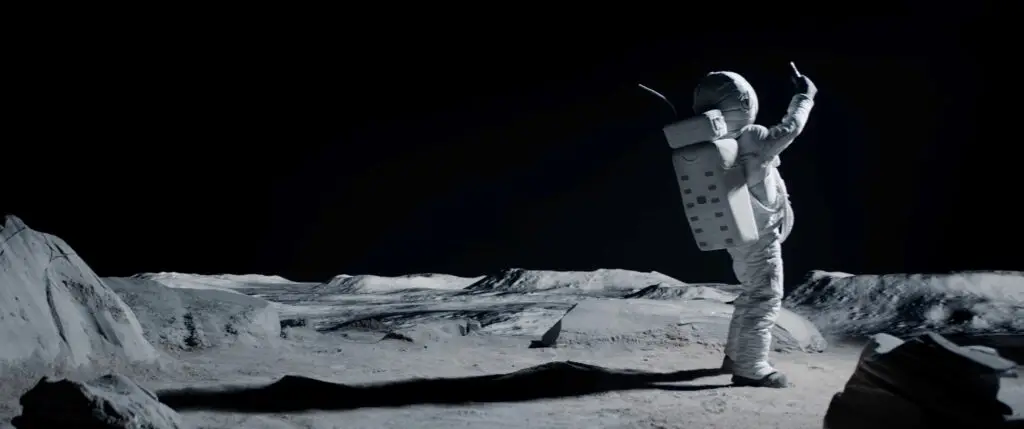 Astronaut auf einer kargen Mondlandschaft mit erhobenem Arm vor tiefschwarzem Himmel.