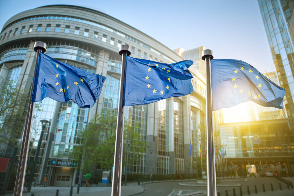 Drei wehende EU-Flaggen vor modernen Gebäuden